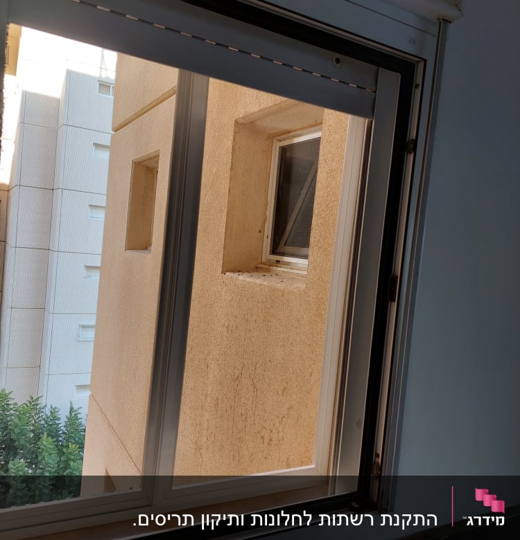 חלון אלומיניום פתוח עם מסגרת לבנה